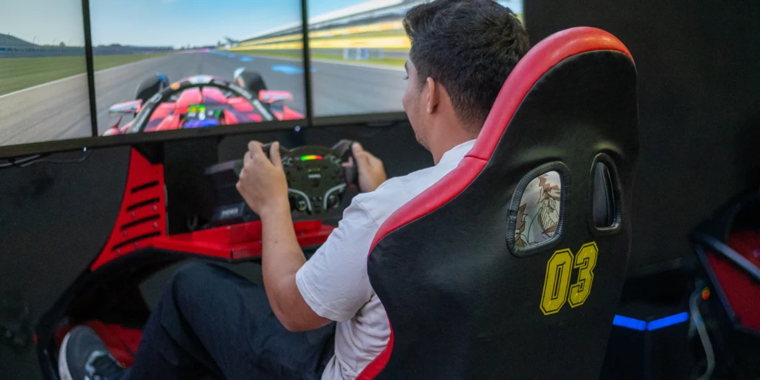 A man intensely focused on a racing simulator, gripping the steering wheel while playing a racing video game