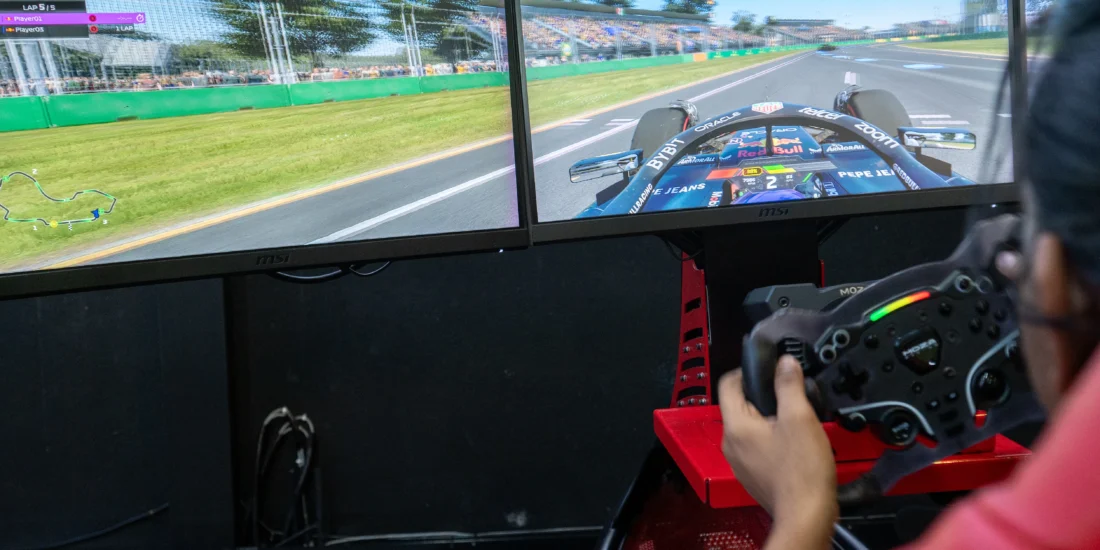 A man intensely focused on playing a racing game on his computer, with a game controller in hand and a screen displaying the race