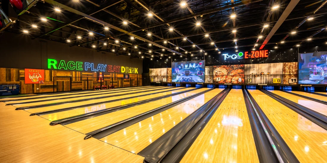 Interior of a bowling alley with a bowling lane and a large screen for displaying scores and entertainment