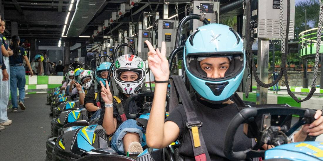 A group of people wearing helmets racing in go-karts on a track, showcasing excitement and competition