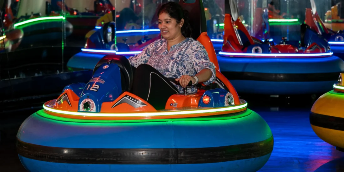A woman rides an amusement park attraction, her expression filled with joy and excitement as she takes in the experience