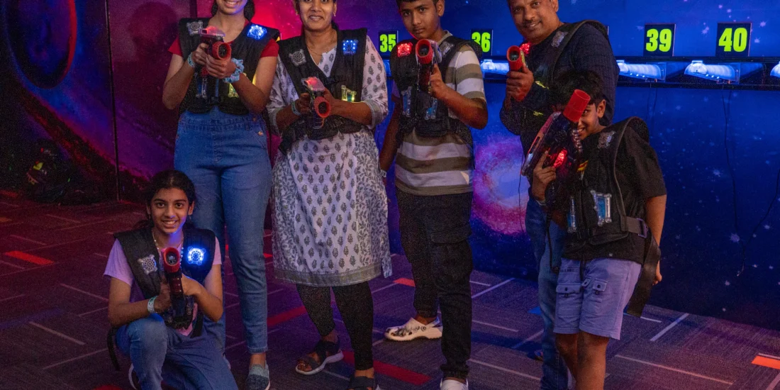 A group of individuals standing together, each holding a firearm, smiling at the camera