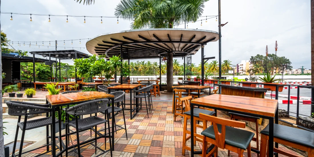Outdoor patio at the hotel bar featuring tables, chairs, and greenery, ideal for relaxing and socializing