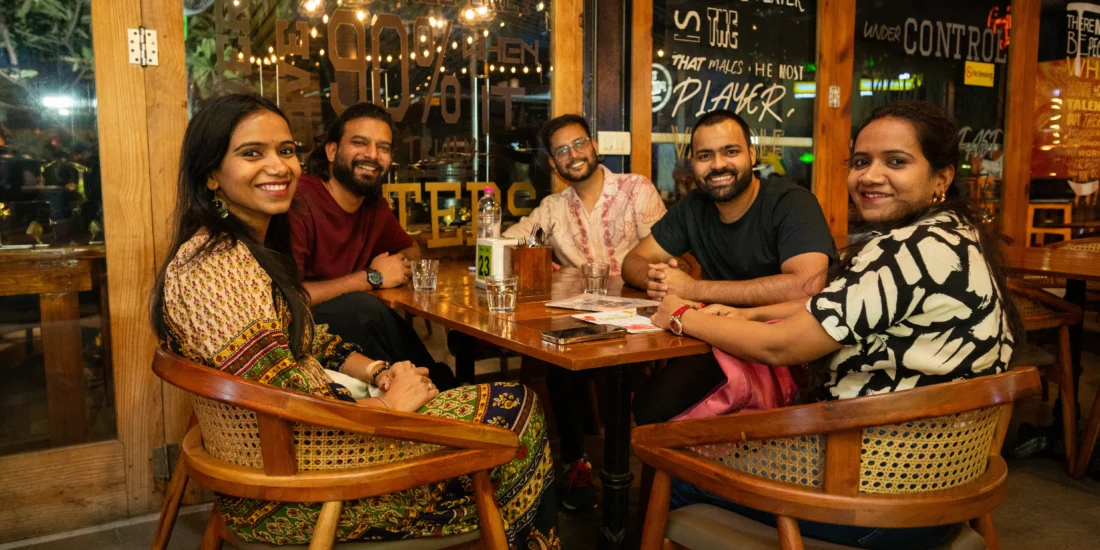 Several people gathered at a restaurant table, sharing food and conversation in a lively dining atmosphere