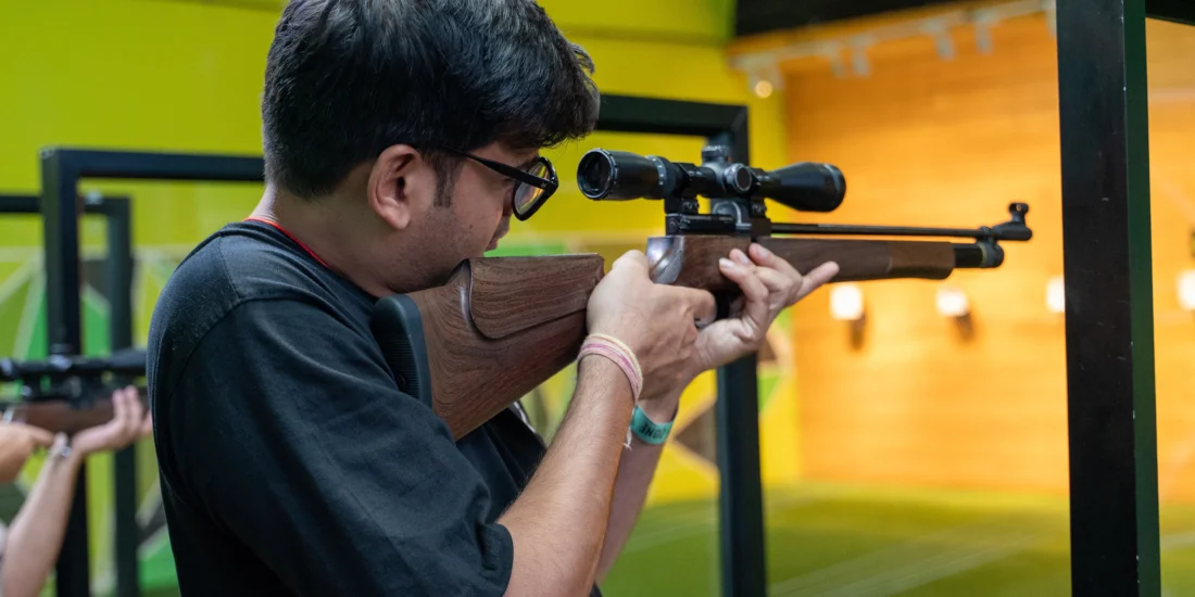 A man is positioned with a rifle, carefully aiming at a distant target