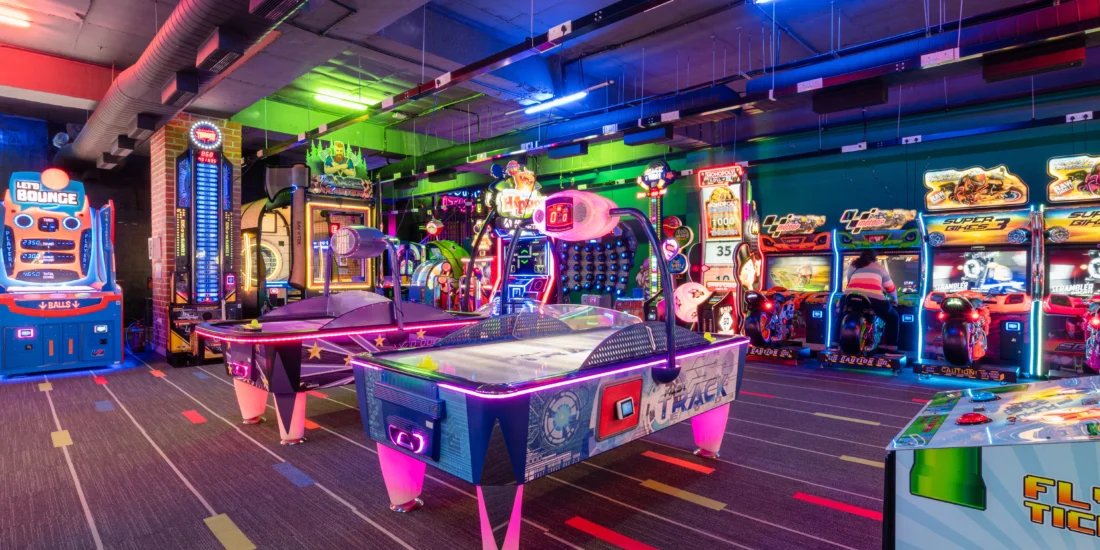 An indoor arcade featuring a variety of games and arcade machines, bustling with energy and excitement for visitors
