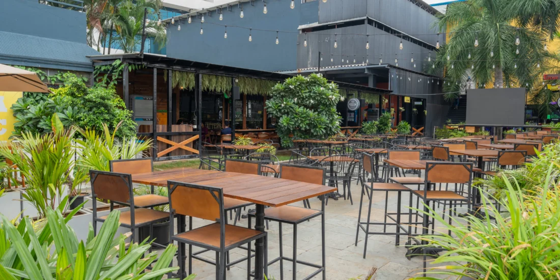 An outdoor hotel patio is enveloped by a variety of plants, providing a tranquil and inviting atmosphere