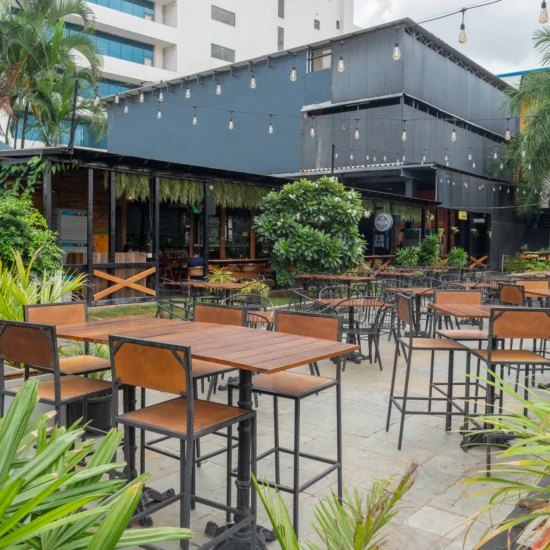 An outdoor hotel patio is enveloped by a variety of plants, providing a tranquil and inviting atmosphere