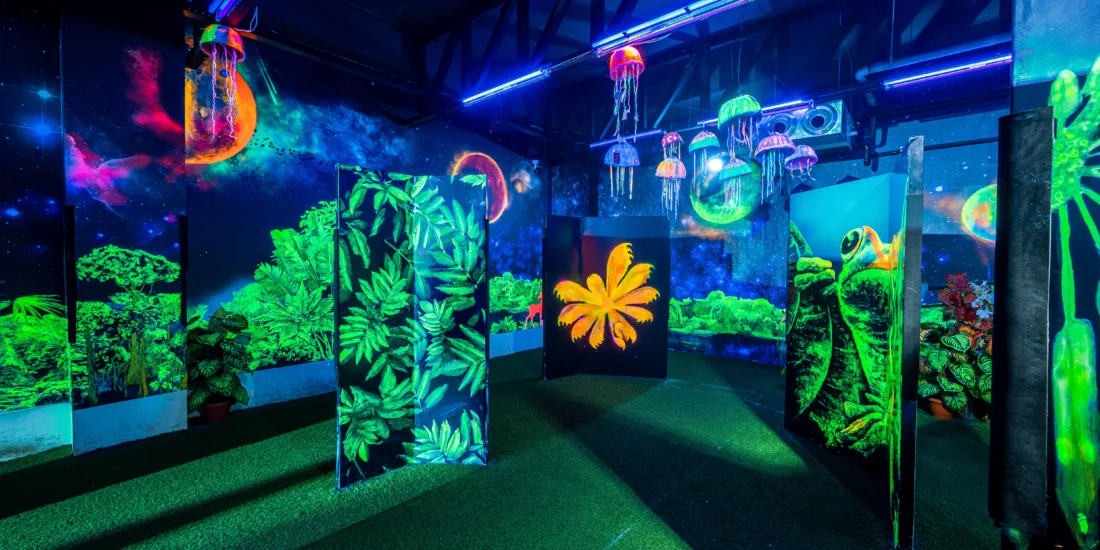 A vibrant room illuminated by neon lights, featuring various green plants throughout the space