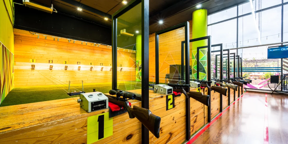 Interior of a gun range with wooden walls and a striking green wall, designed for shooting practice