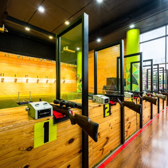 Interior of a gun range with wooden walls and a striking green wall, designed for shooting practice