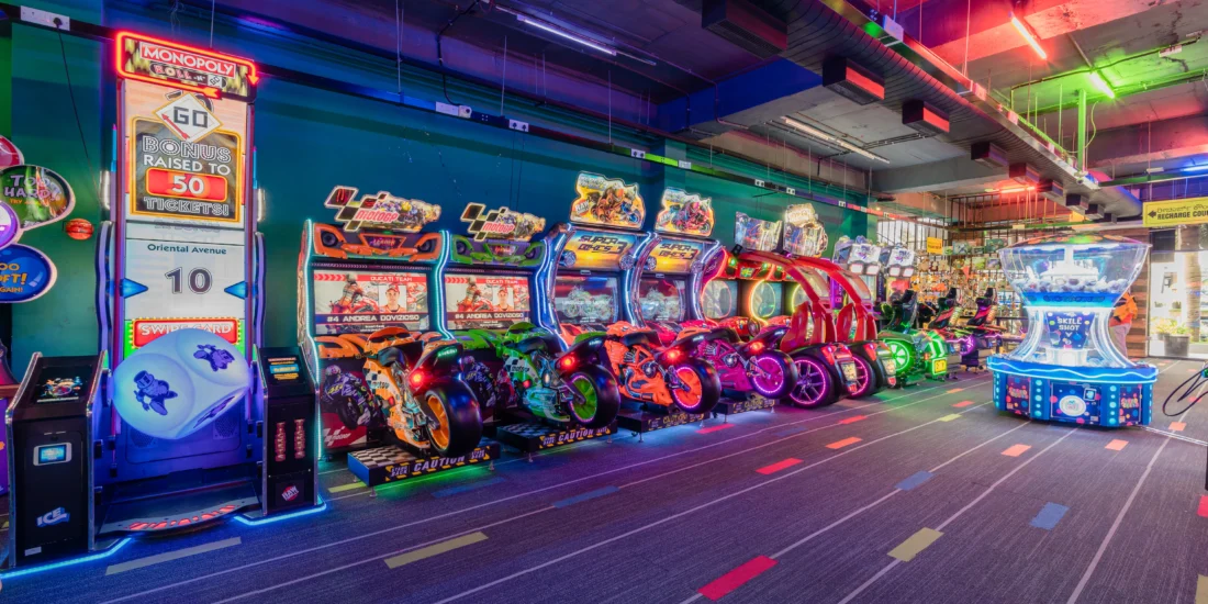 A large arcade featuring numerous game stations, vibrant decorations, and players engaged in various gaming activities