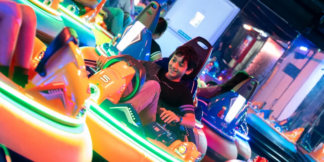 A cheerful group of individuals in bumper cars at a carnival, engaging in friendly collisions amidst a lively, colorful setting