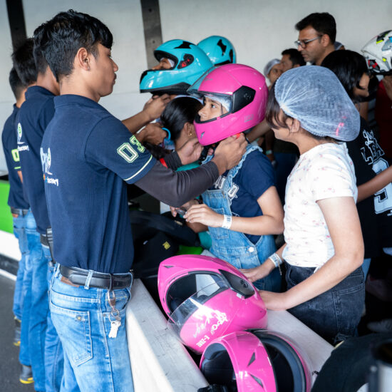 A group of people in helmets proudly holding their helmets above their heads, smiling and celebrating together