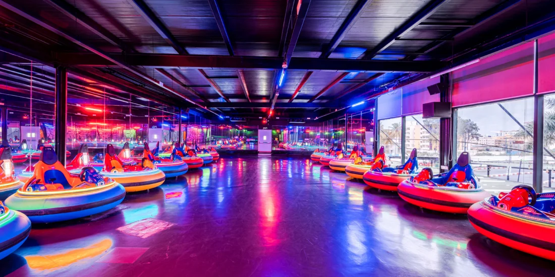 A large indoor bumper car attraction featuring bright neon lights, creating a lively and fun atmosphere for riders