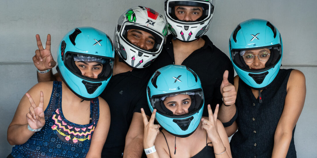 Several individuals in helmets stand together, smiling for a group photo, highlighting their teamwork and safety precautions ready to ride for Go Karting