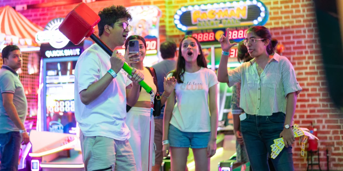 A group of people gathered around a pinball machine, focused on playing and enjoying the game together